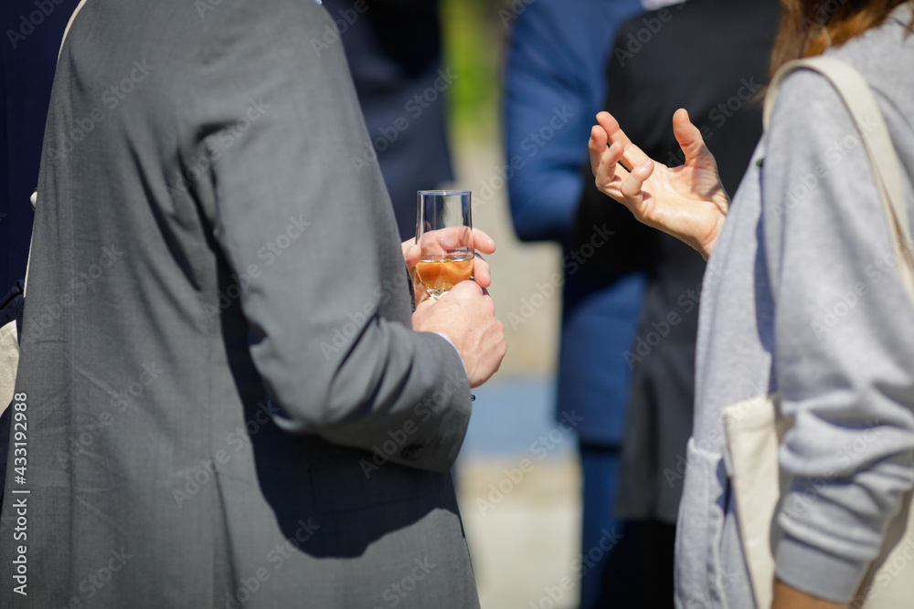 Details with a man and a woman interacting at a classy event, while holding a glass of wine.