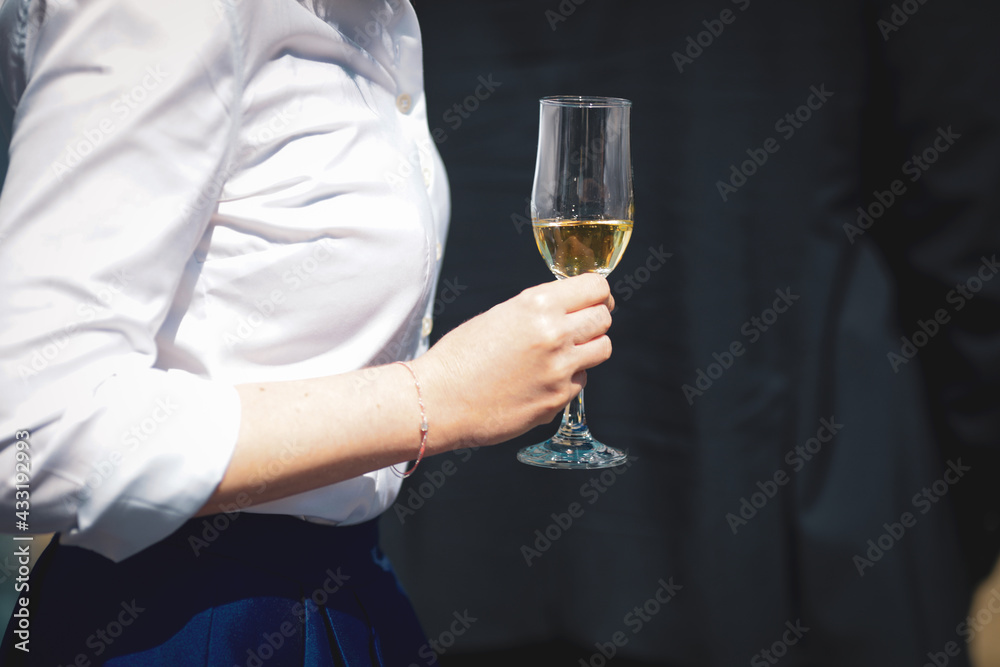 Details with the hands of a woman interacting at a classy event, while holding a glass of wine. Details with the hands of a woman interacting at a classy event, while holding a glass of wine.
