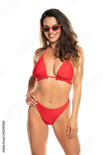 front view of a young beautiful smiling woman posing in a red swimsuit and sunglasses © vladimirfloyd