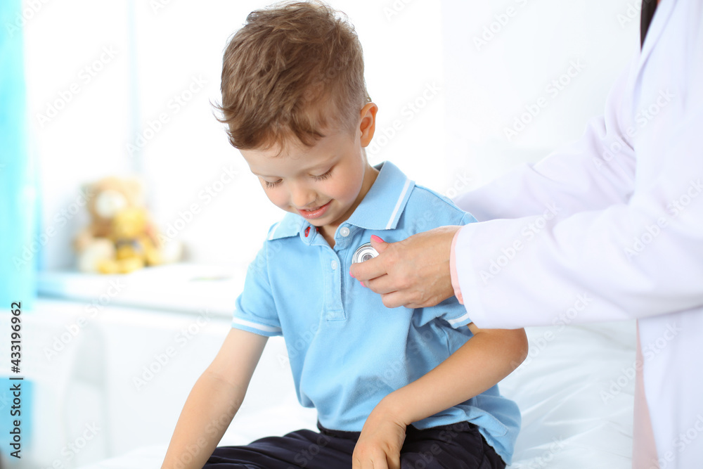 Happy smiling male kid-patient at usual medical inspection. Doctor and young boy in the clinic. Medicine concepts