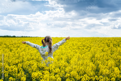 Close up rear view of a beautiful girl in a rapeseed field. A child in a blooming field with yellow flowers. © Jess_Ivanova