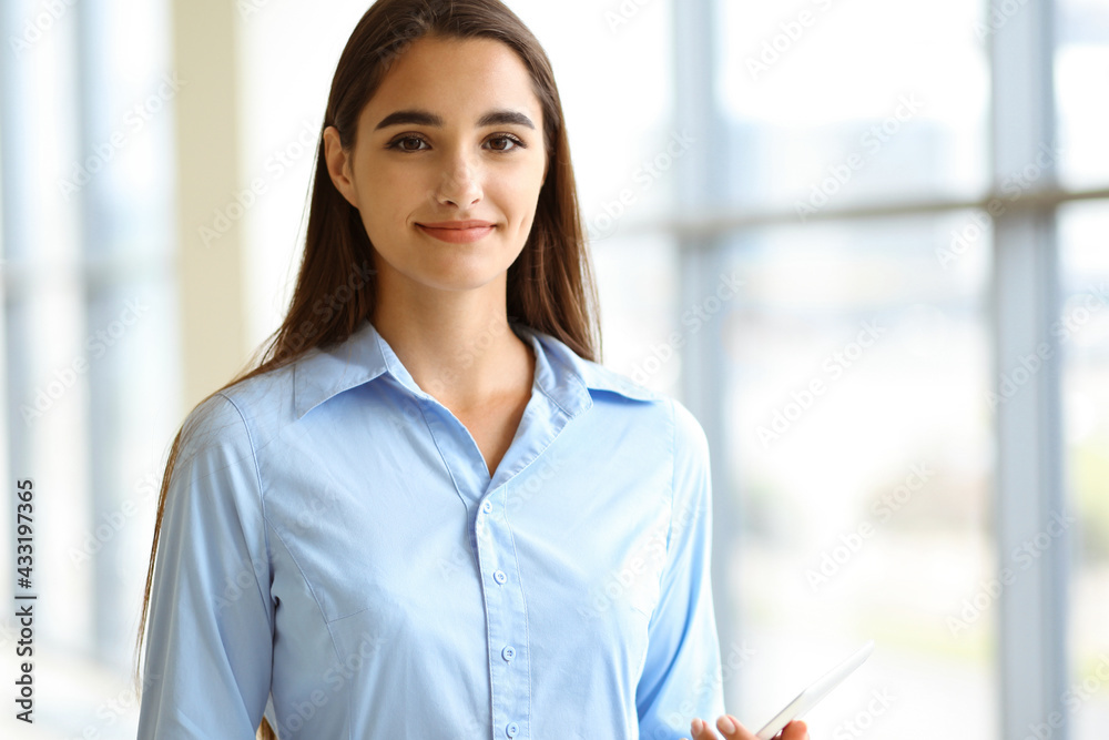 A friendly young dark hair businesswoman or female student is standing with some papers in the office A friendly young dark hair businesswoman or female student is standing with some papers in the office