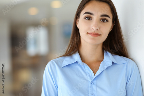 A friendly young dark hair businesswoman or female student is standing with some papers in the office