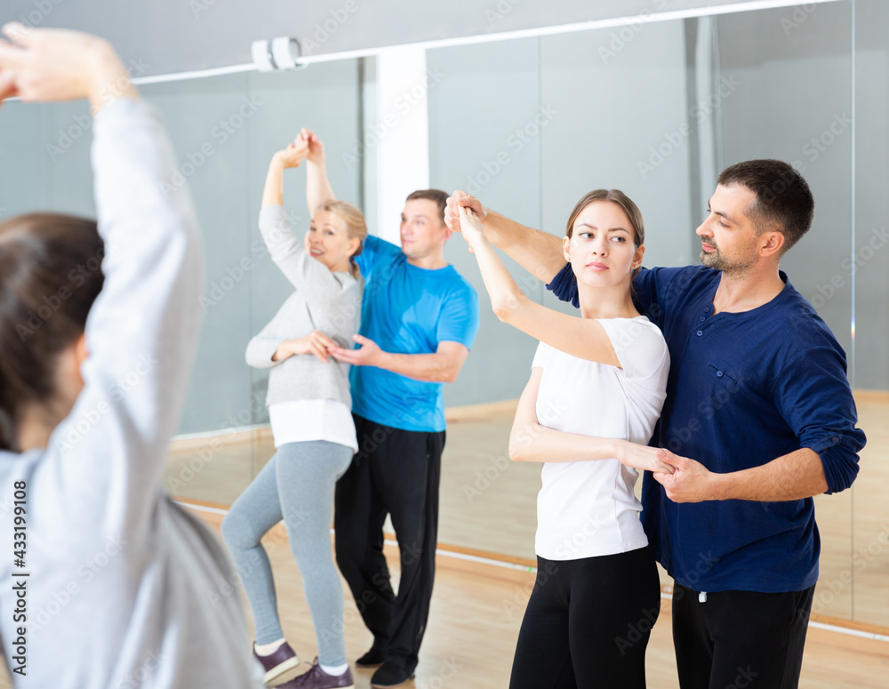 Fototapeta premium Group of happy adult people dancing modern social dances in pair at .dance school