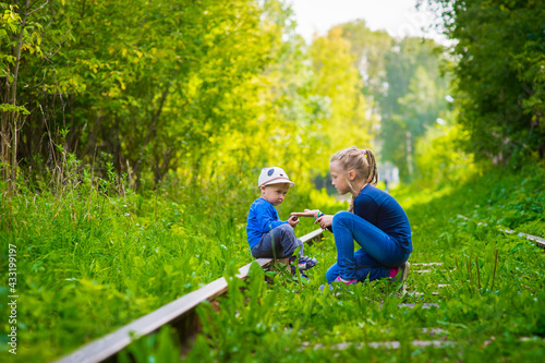 girl and boy sitting on an old railroad, summer, outdoor walks happy childhood selective focus