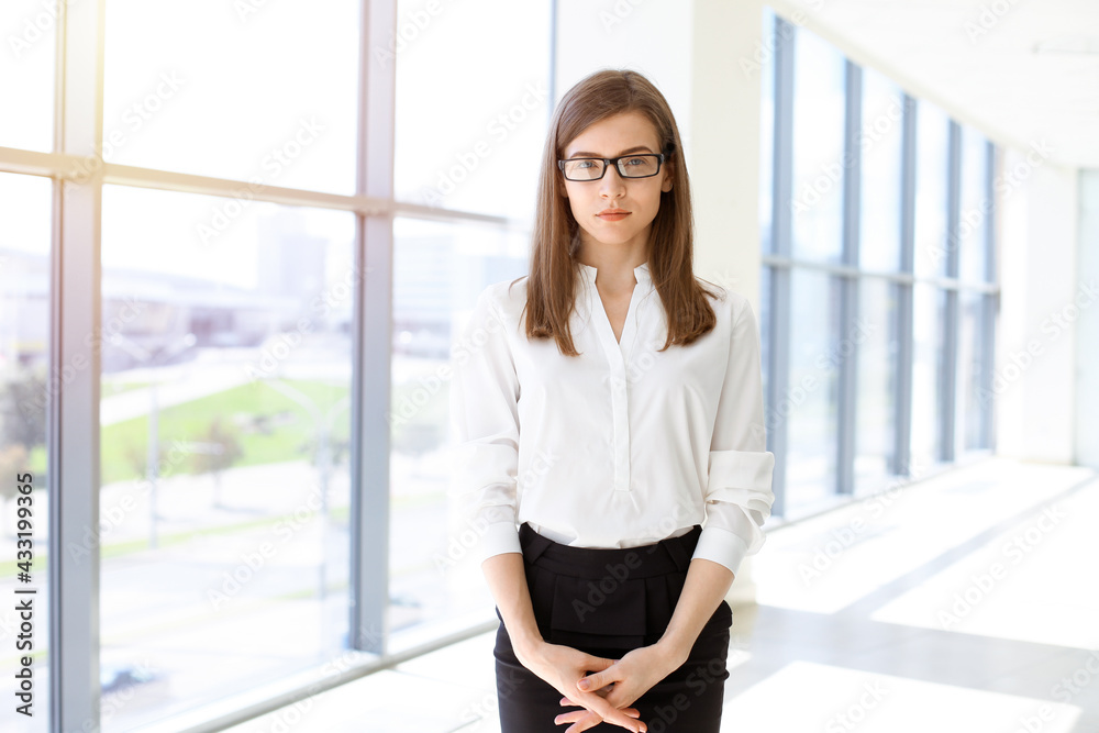 Beautiful female specialist with dark hair standing in sunny office and smiling charmingly. Working on design, data analysis, plan strategy Beautiful female specialist with dark hair standing in sunny office and smiling charmingly. Working on design, data analysis, plan strategy
