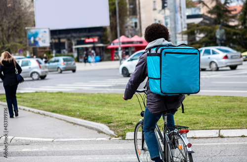Male courier with bicycle delivering packages in city.