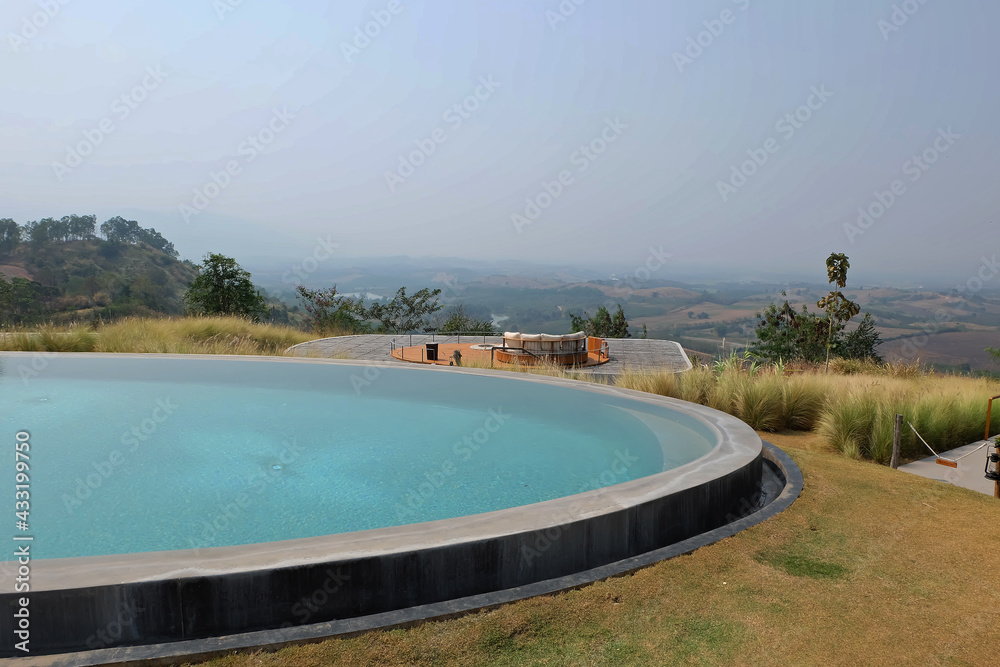 Exterior architecture and decoration of swimming pool design with green mountain view and cloudy blue sky