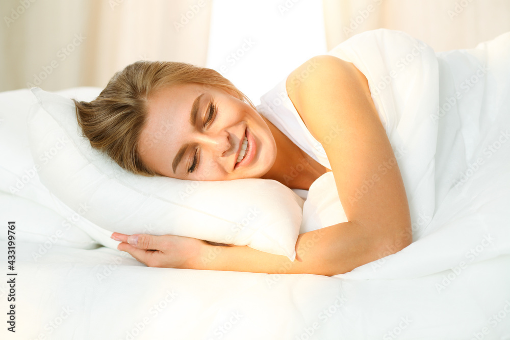 Beautiful blonde girl sleeping sweetly in sunny bedroom on a white bed. Holyday comfort and Rest concepts Beautiful blonde girl sleeping sweetly in sunny bedroom on a white bed. Holyday comfort and Rest concepts