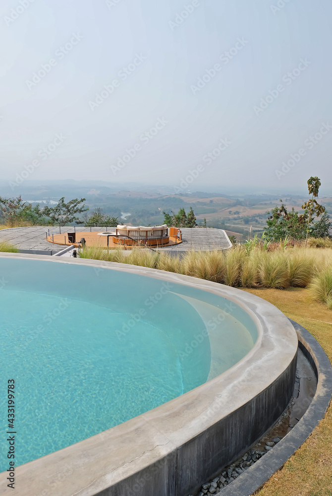 Fototapeta premium Exterior architecture and decoration of swimming pool design with green mountain view and cloudy blue sky