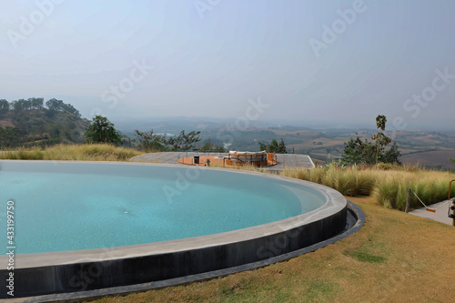 Fototapeta Naklejka Na Ścianę i Meble -  Exterior architecture and decoration of swimming pool design with green mountain view and cloudy blue sky