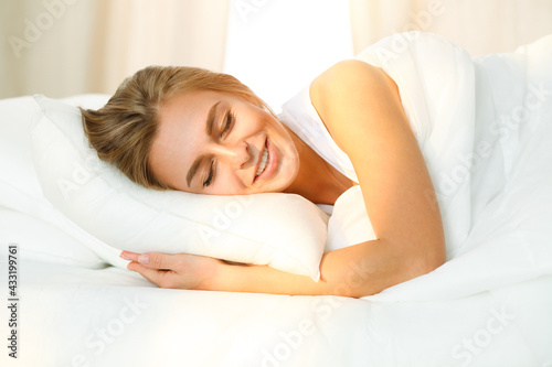Beautiful blonde girl sleeping sweetly in sunny bedroom on a white bed. Holyday comfort and Rest concepts