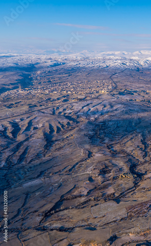 Aerial view of amazing landscapes with rock formations, snow-capped mountains, and the town of Ürgüp in Cappadocia, Turkey