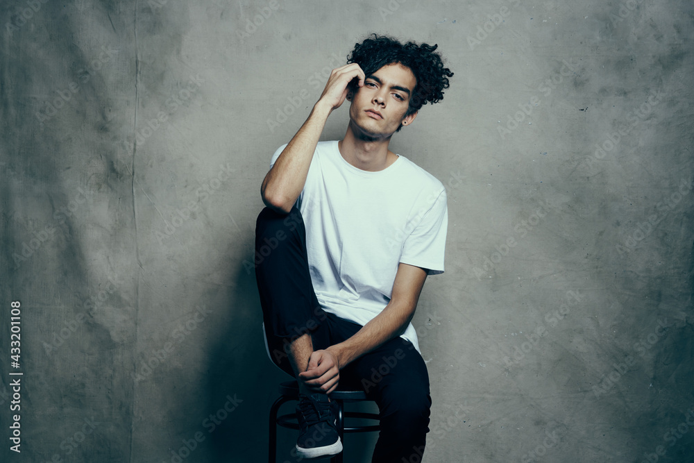man in white t-shirt sits on chairs fashion curly hair lifestyle man in white t-shirt sits on chairs fashion curly hair lifestyle