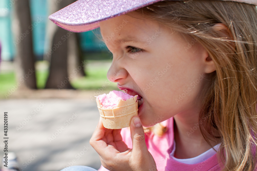 Little happy girl walking in the park in summer and eating ice cream. High quality photo