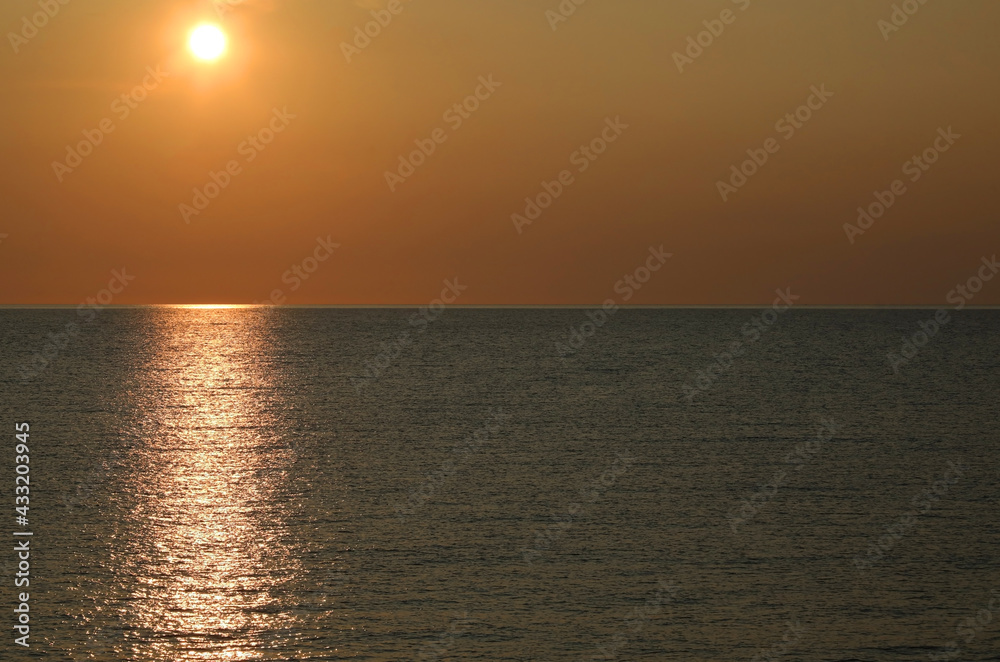 sunset on the sea with warm orange red tones and sun reflection on the water