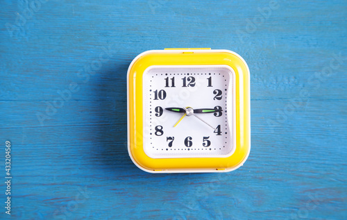 Yellow clock on blue wooden background.