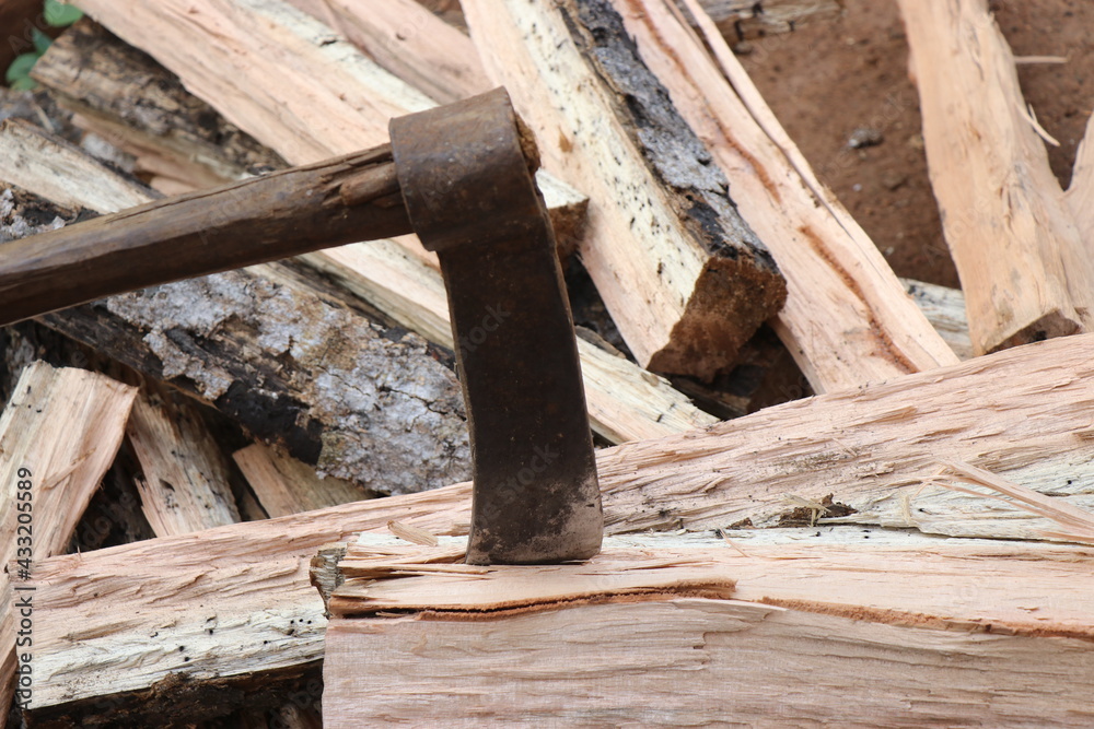 Old and rusty axe with wooden handle stuck on piece of wood. Axe for timber works Old and rusty axe with wooden handle stuck on piece of wood. Axe for timber works