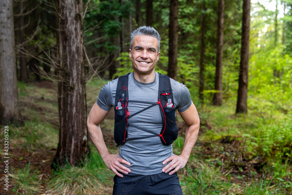 portrait of male trailrunner smiling at camera in a forest portrait of male trailrunner smiling at camera in a forest