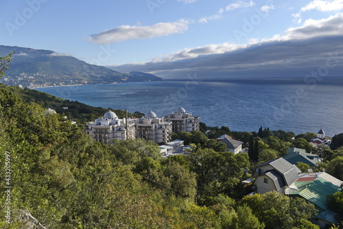 Yalta, Crimea - 10.16.2015 : Different types of vegetation in a mountainous area against the background of buildings near the Black Sea coast.