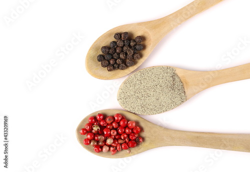 Red and black peppercorns and ground white pepper pile in wooden spoons isolated on white background, top view