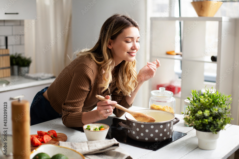 Attractive woman cooking in modern kitchen. Beautiful woman cooking  delicious food at home. Stock Photo | Adobe Stock