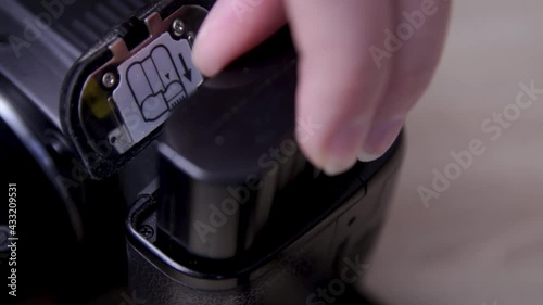 Photographer inserts battery into professional camera. Professional artist has run out of battery life in camera while shooting pictures