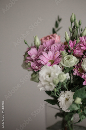 Beautiful bouquet of spring flowers. Delicate bouquet of pink and white flowers. Pink peony roses, purple chrysanthemum, white roses. Spring colors on grey background.