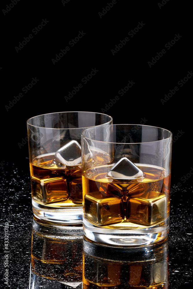 Whiskey with steel cooling cubes on dark glass background