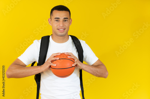 happy handsome student holding a basketball isolated over white background. © Danko