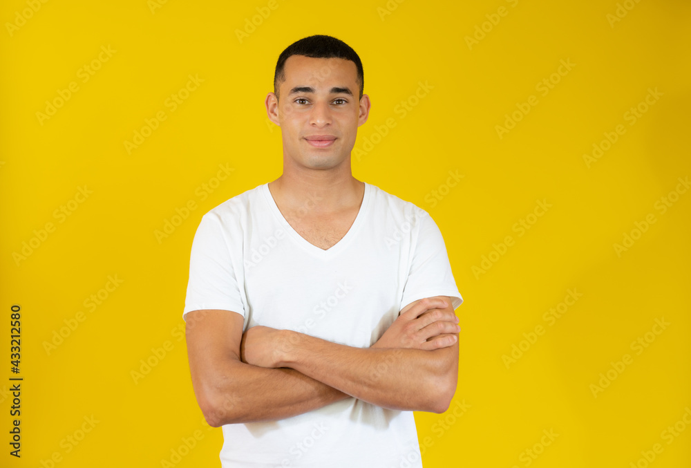 Attractive young man in casual t-shirt with arms folded isolated over yellow background. Attractive young man in casual t-shirt with arms folded isolated over yellow background.