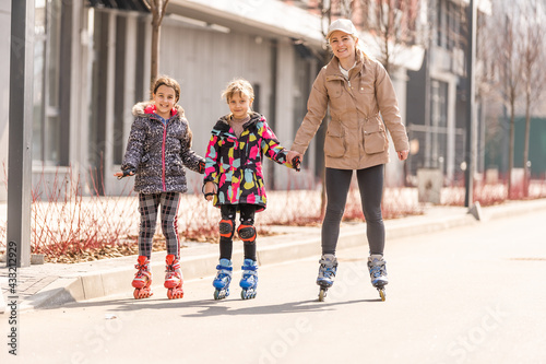 A happy family in roller skates, mother two and two daughters on roller skates