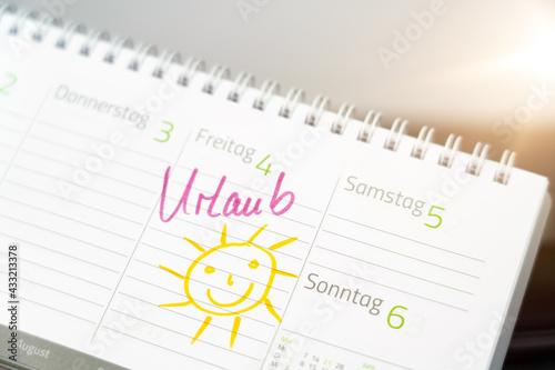 The entry of the German word for vacation and the drawing of a smiling sun in a desk calendar