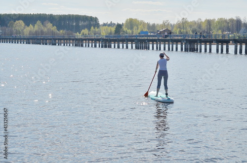 Girl on open water SUP on the background of the bridge and the banks