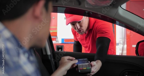 Hand of customer paying with contactless credit card with NFC technology to worker of gas station for payment terminal while sitting in the car, credit card reader machine. photo
