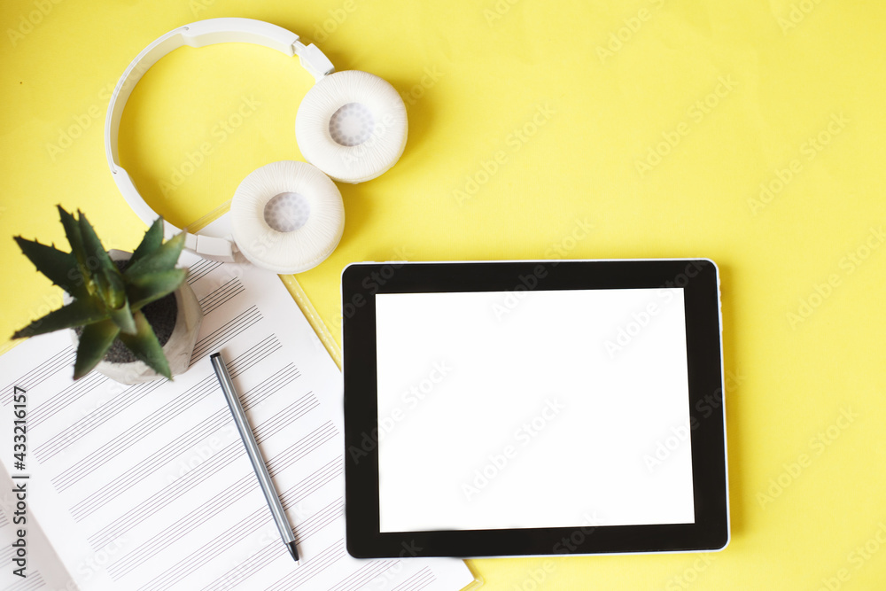Top view open music book, headphones and a pen on a yellow background. mock up for music lessons