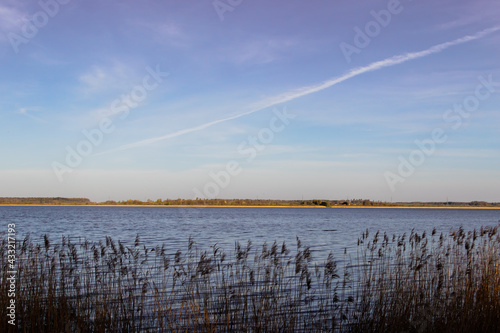 View of Lake Durbe with reeds in the foreground. Blue water and sky without big clouds with airplane tracks. photo