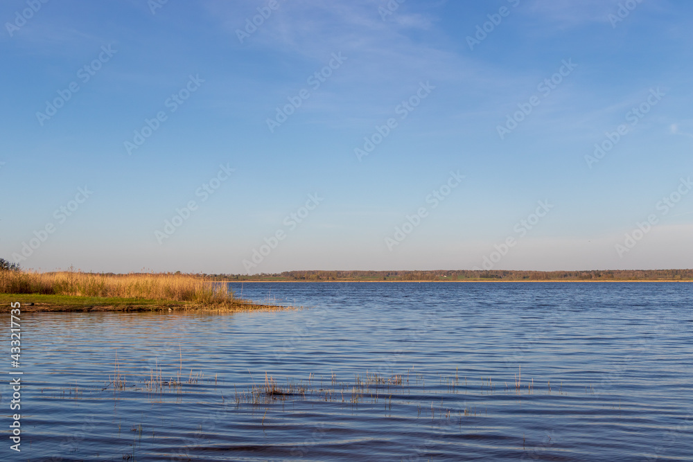 View of Lake Durbe with reeds in the foreground. Blue water and sky without clouds.