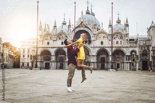 Couple of tourists visiting Venice, Italy - Boyfriend and girlfriend in love having fun on city street at sunset - People, love and holidays concept © Davide Angelini