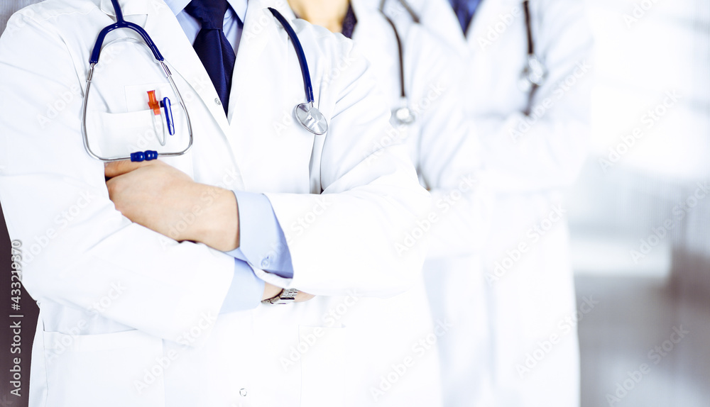 Group of modern doctors standing as a team with crossed arms and stethoscopes in hospital office. Physicians ready to examine and help patients. Medical help, insurance in health care, best desease