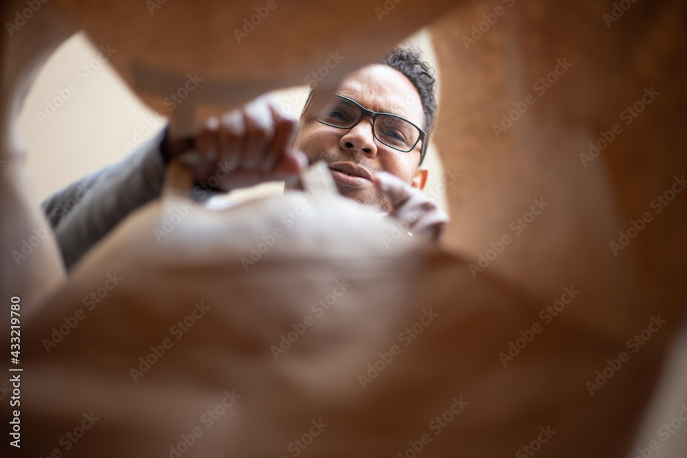 Obraz premium latin man opening box at home due to pandemic