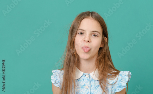 white girl 10 years old showing her tongue, fooling around on a green background