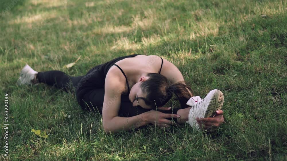Young athletic woman doing stretching in the park before training. Side view. Young athletic woman doing stretching in the park before training. Side view.