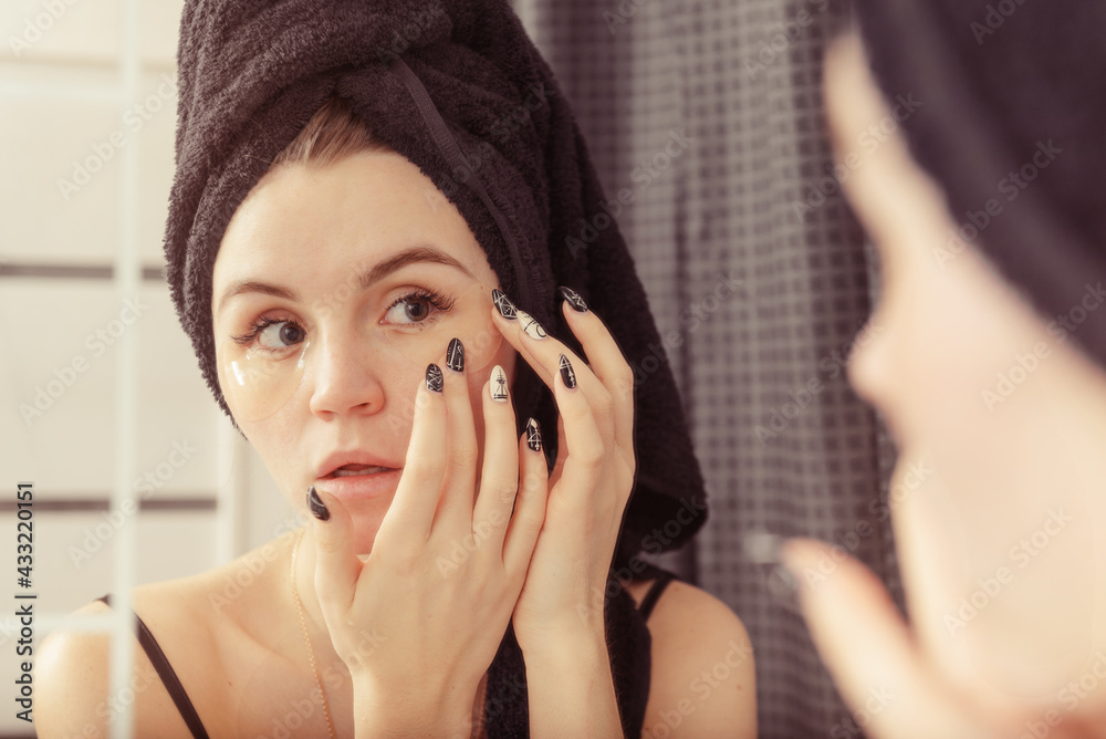 white young woman with a black towel on her head puts patches on her eyes white young woman with a black towel on her head puts patches on her eyes