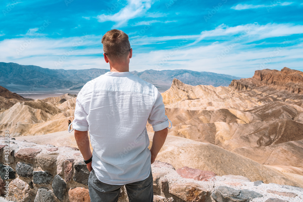 Rear view of a young blond man in Death Valley with a view of Zabriskie Point, USA Rear view of a young blond man in Death Valley with a view of Zabriskie Point, USA