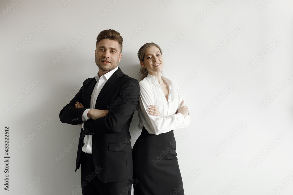 A man and a woman standing back to back on a white background. Business portrait of a couple in a business style. A man and a woman standing back to back on a white background. Business portrait of a couple in a business style.