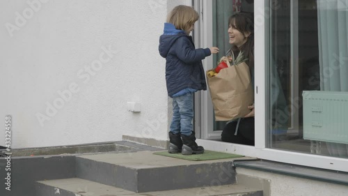 Wallpaper Mural Funny little child give a paper bag with groceries to mother sitting at door, Torontodigital.ca