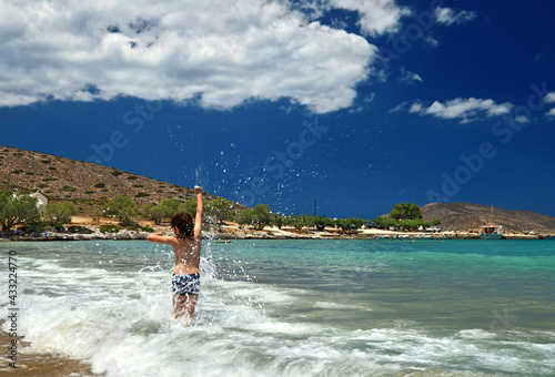 Fototapeta Naklejka Na Ścianę i Meble -  Boy playing with the waves at Tholos beach, close to Kavousi village, Ierapetra municipality, Crete, Greece.