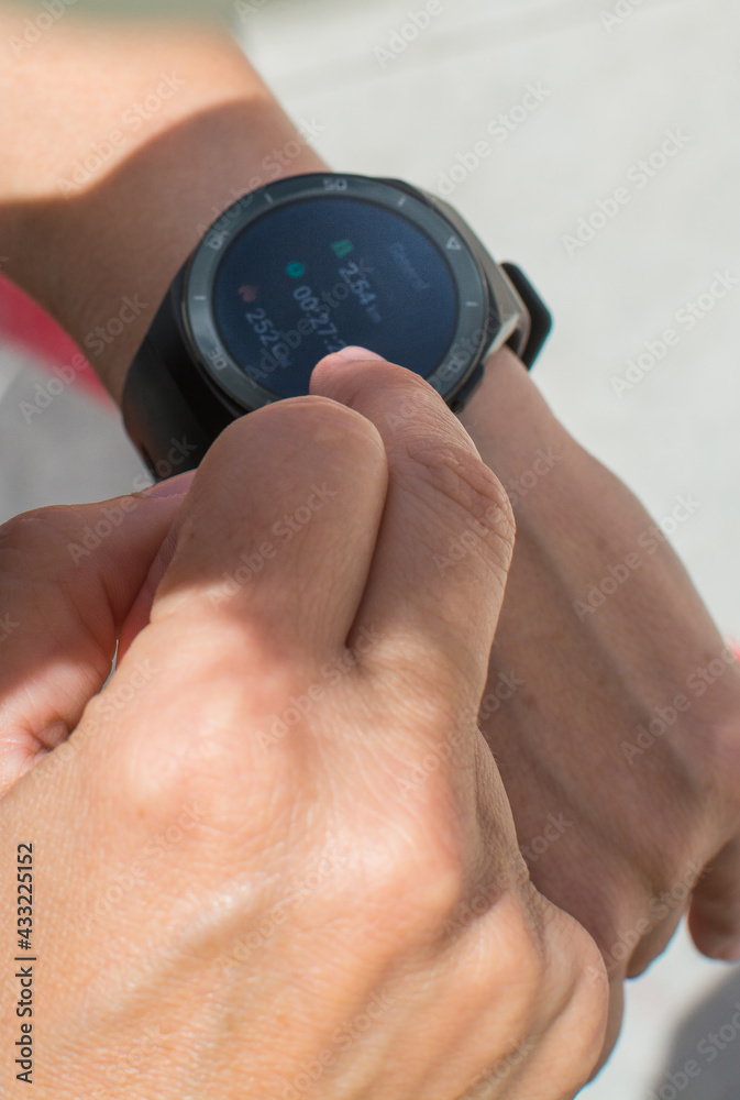 Fototapeta premium Unrecognizable Sportswoman Checking Smart Watch. Female Athlete Using Smart Watch On Wrist During Fitness Training On Street. 
