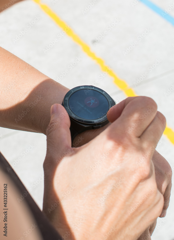 Fototapeta premium Unrecognizable Sportswoman Checking Smart Watch. Female Athlete Using Smart Watch On Wrist During Fitness Training On Street. 